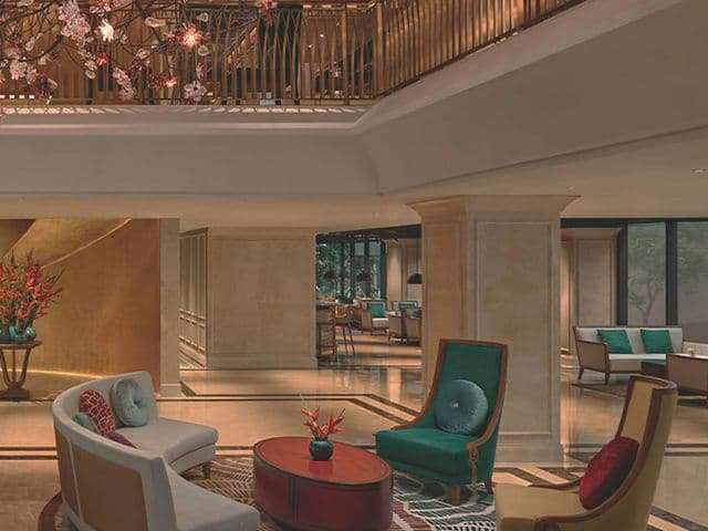 Elegant lounge at 369 Dine & Bar with green velvet armchairs, curved sofa and a mezzanine balcony with blossom branches