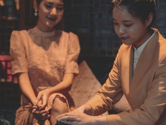 Woman in a tan blazer prepares tea as a guest in a lace dress watches at 369 Dine & Bar