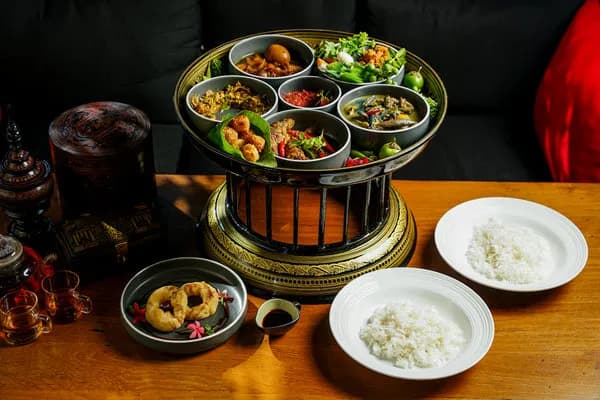 Tiered brass tray of Burmese curries and salads with rice, fried fritters and tea at Café Salween