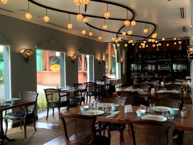 Обеденный зал Le Planteur Restaurants & Lounge с плетёными стульями, сервированными столами и шарообразными светильниками