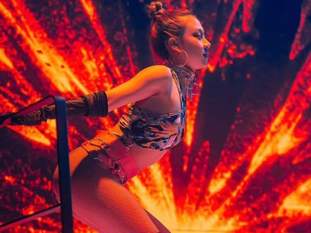 Dancer in a sequined crop top and long black gloves performs before a fiery red LED screen at Levels Club & Lounge