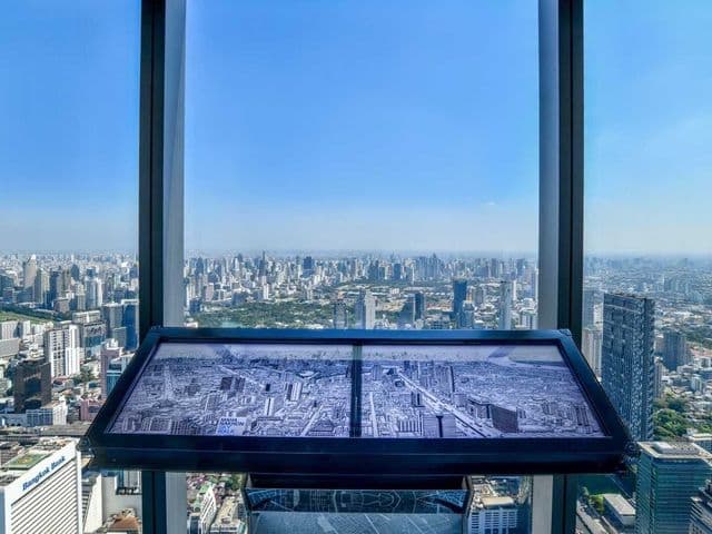 Panoramic Bangkok skyline through floor-to-ceiling windows, with a city map display panel at Mahanakhon SkyBar