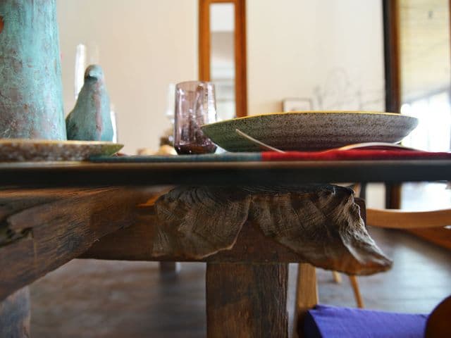 SEEDS Restaurant & Lounge の素朴な木のテーブルに並ぶ斑点模様の陶器の皿とグラスをローアングルで