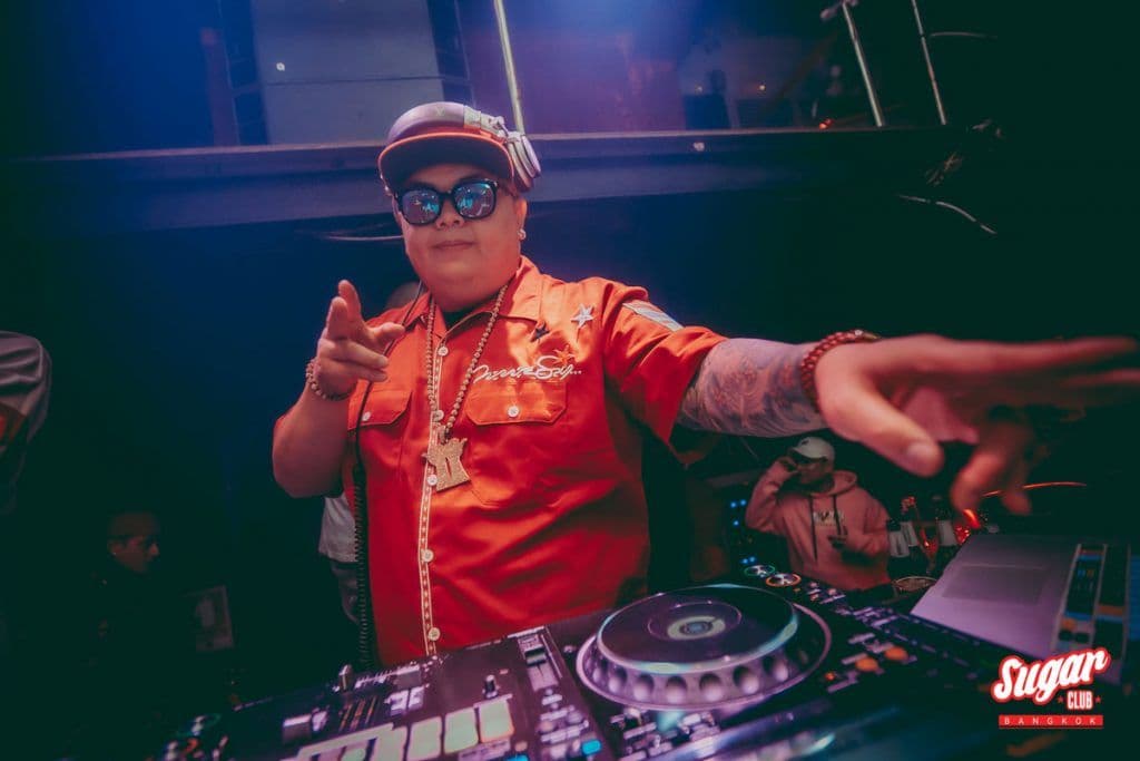 Sugar Club Bangkokで赤いシャツにキャップとサングラス姿のDJがターンテーブル越しに指を差す