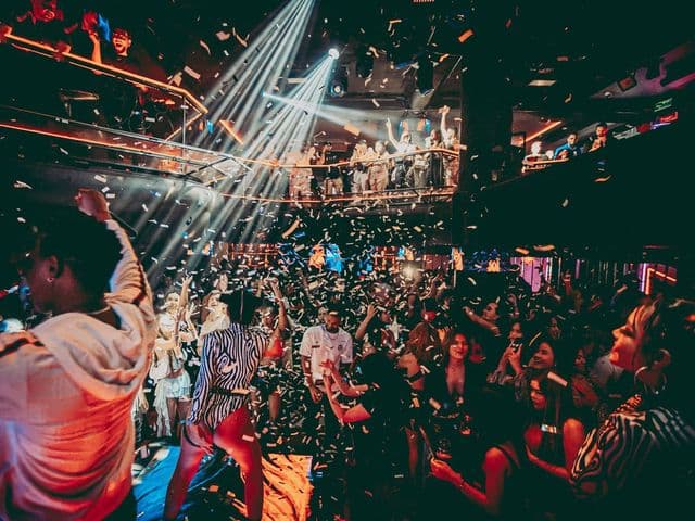 スポットライトと舞い散る紙吹雪の下、満員のダンスフロアとバルコニーで盛り上がる客たち（Sugar Club Bangkok）