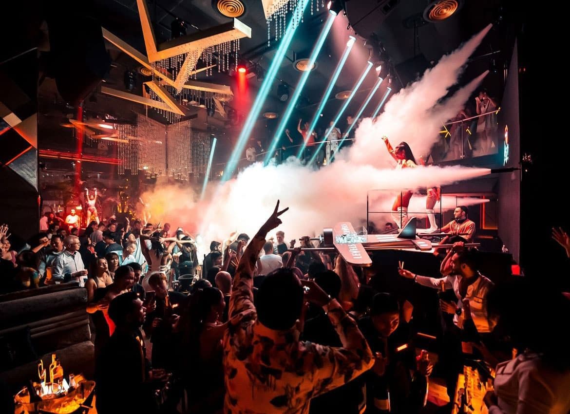 Packed dance floor with CO2 smoke jets, light beams and a DJ booth at Levels Club & Lounge
